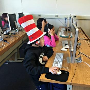 Boy wearing a Cat in the Hat Cap working on a computer